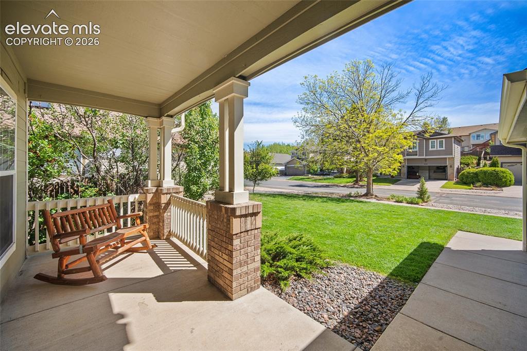 Image 3 of 45: Covered concrete front porch featuring brick-wrapped columns, painted raili
