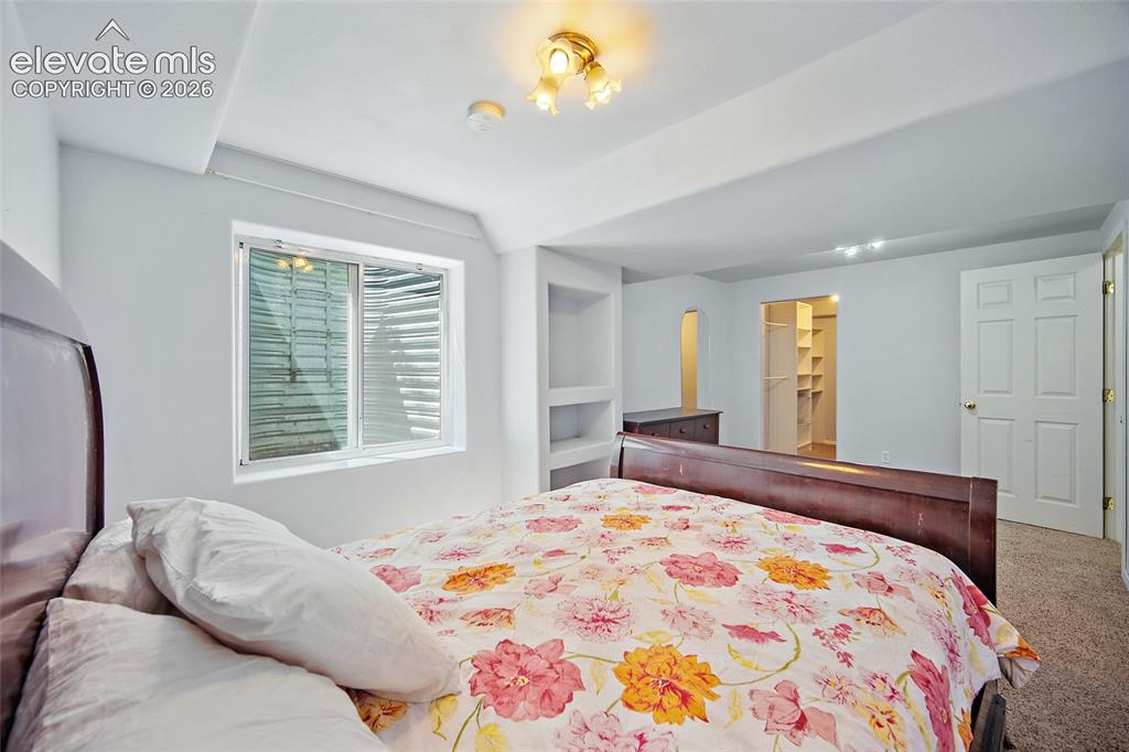 Image 31 of 45: Bedroom featuring a window, built-in shelving, a walk-in closet with shelvi