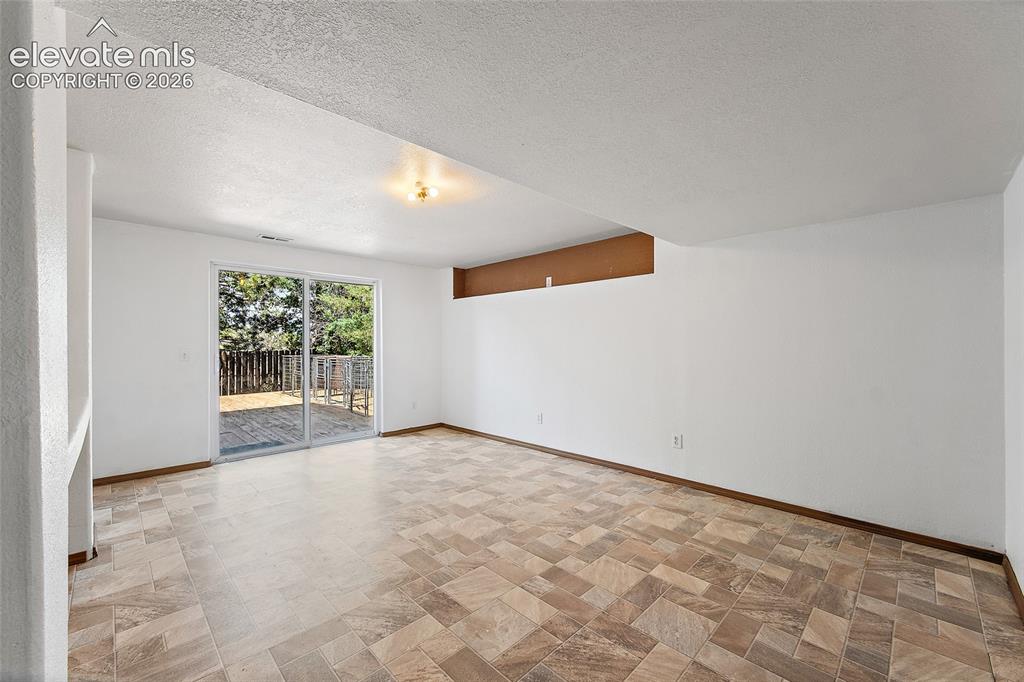 Image 33 of 45: Spacious room featuring tile-finish flooring and a glass sliding door provi