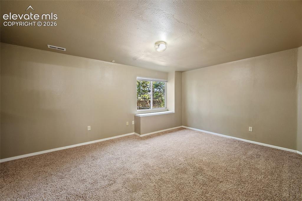 Image 36 of 45: Carpeted room with a window featuring exterior views, neutral wall color, w