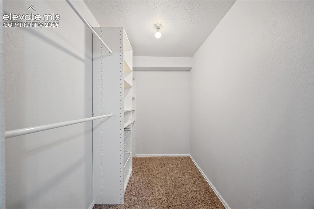 Image 38 of 45: Walk-in closet featuring built-in shelving, dual hanging rods, light-colore