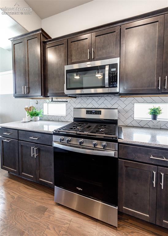Image 10 of 50: Kitchen featuring stainless steel appliances, dark wood cabinetry, white su