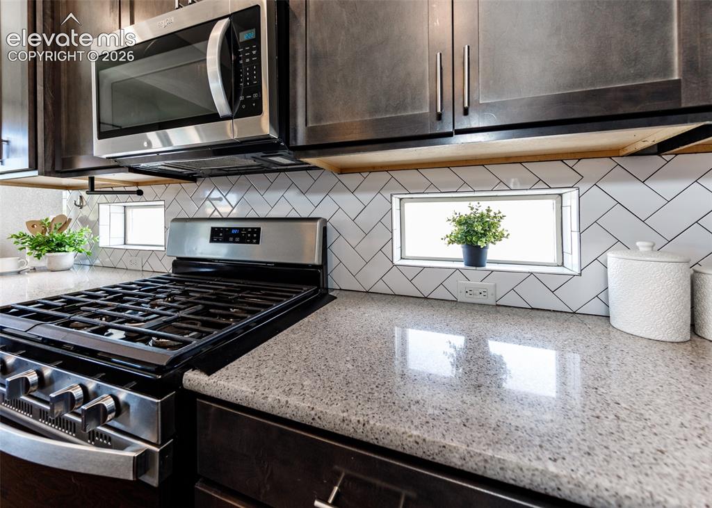 Image 11 of 50: Kitchen featuring a stainless steel range with overhead microwave, white he