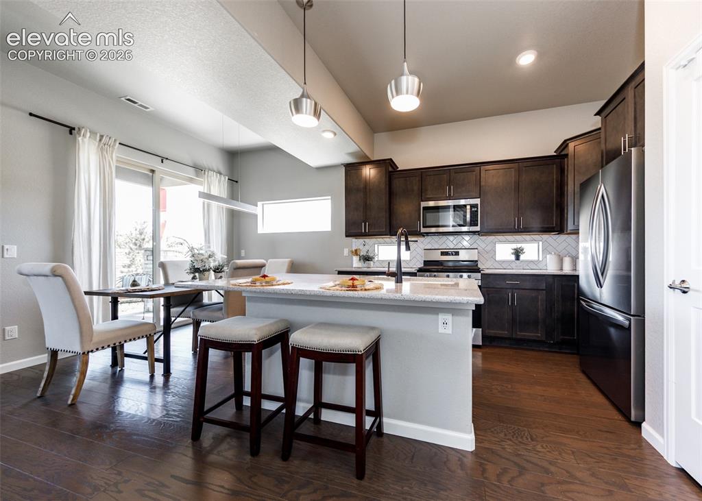 Image 12 of 50: Modern kitchen featuring dark wood cabinetry, stainless steel appliances, a