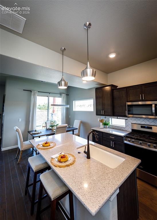 Image 13 of 50: Open-concept kitchen featuring a spacious island with integrated sink, dark