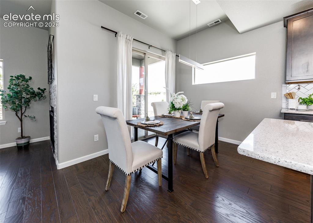 Image 15 of 50: Dining area featuring dark wood-finish flooring and light gray walls