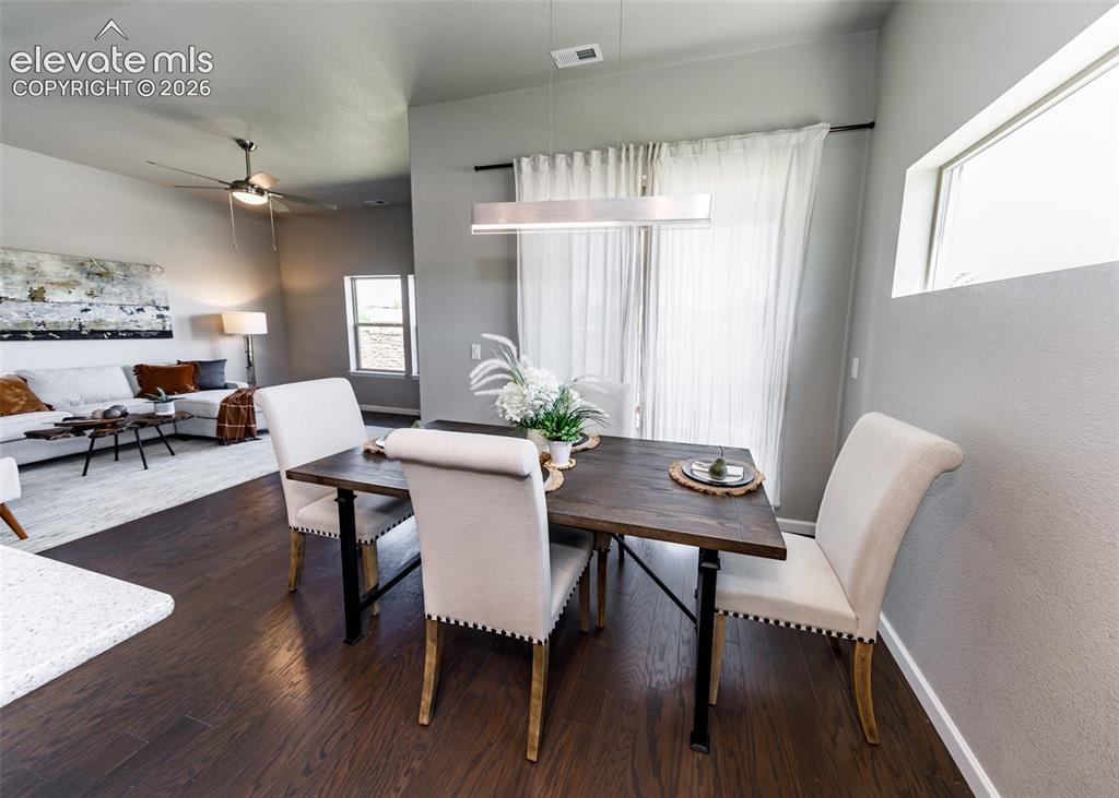 Image 17 of 50: Dining area featuring dark wood-finish flooring, a linear pendant light fix