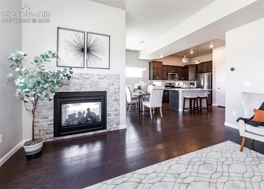Image 24 of 50: Expansive wood-finish flooring complements the gas fireplace with stone til
