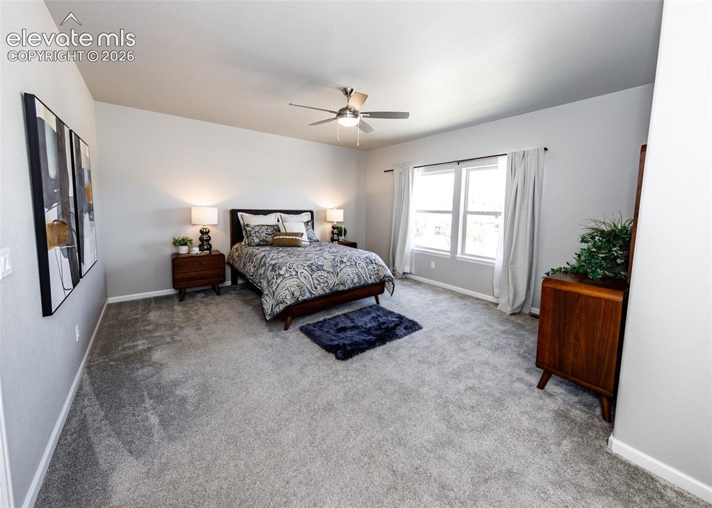 Image 28 of 50: Carpeted room with a vaulted ceiling, a ceiling fan, and dual windows