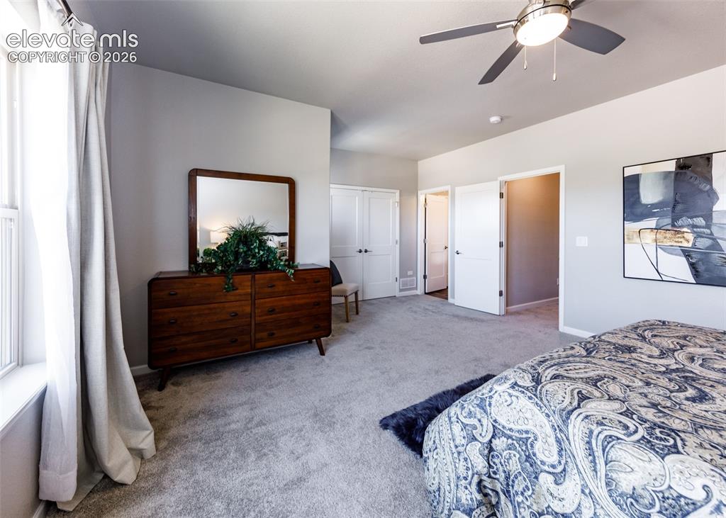 Image 29 of 50: Carpeted bedroom featuring a ceiling fan with integrated lighting, two whit