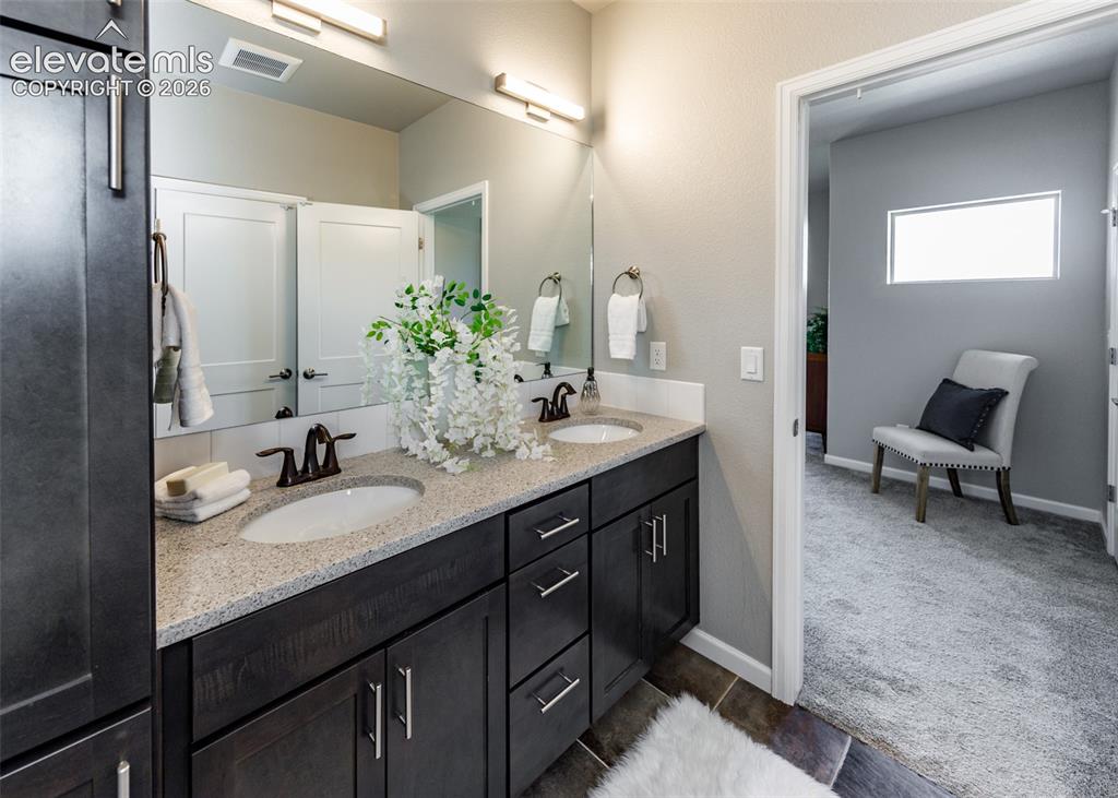 Image 33 of 50: Double vanity with dark wood-finish cabinetry, light speckled countertop, a