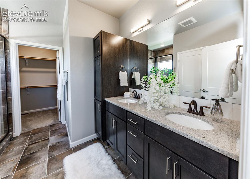 Image 34 of 50: Dual vanity with integrated sinks, light-toned countertop, and dark wood-fi