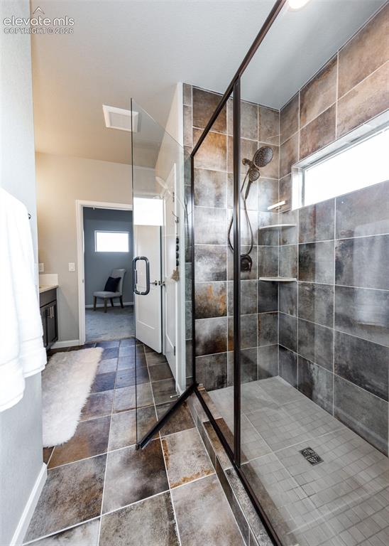 Image 36 of 50: Spacious walk-in shower featuring a frameless glass enclosure with matte bl