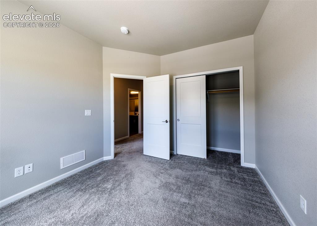 Image 38 of 50: Carpeted interior room with light gray walls