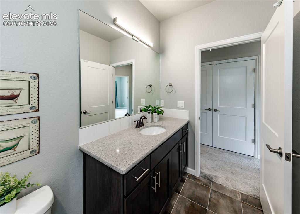 Image 41 of 50: Bathroom vanity featuring a single basin sink, contemporary dark cabinetry,