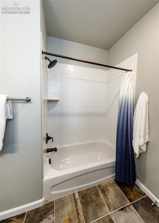 Image 43 of 50: Bathtub and shower combination featuring white subway tile surround, dark b
