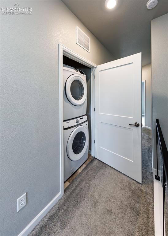 Image 44 of 50: Stacked front-load washer and dryer within a dedicated closet, featuring a 