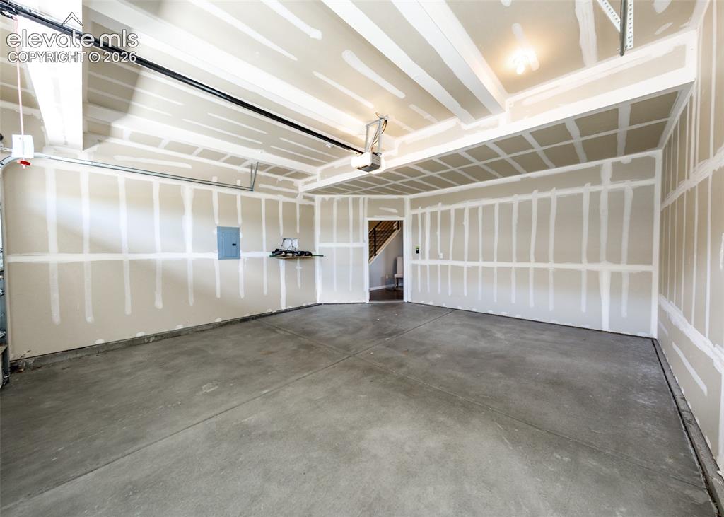 Image 45 of 50: Spacious garage with concrete flooring, drywall-finished walls, and an over