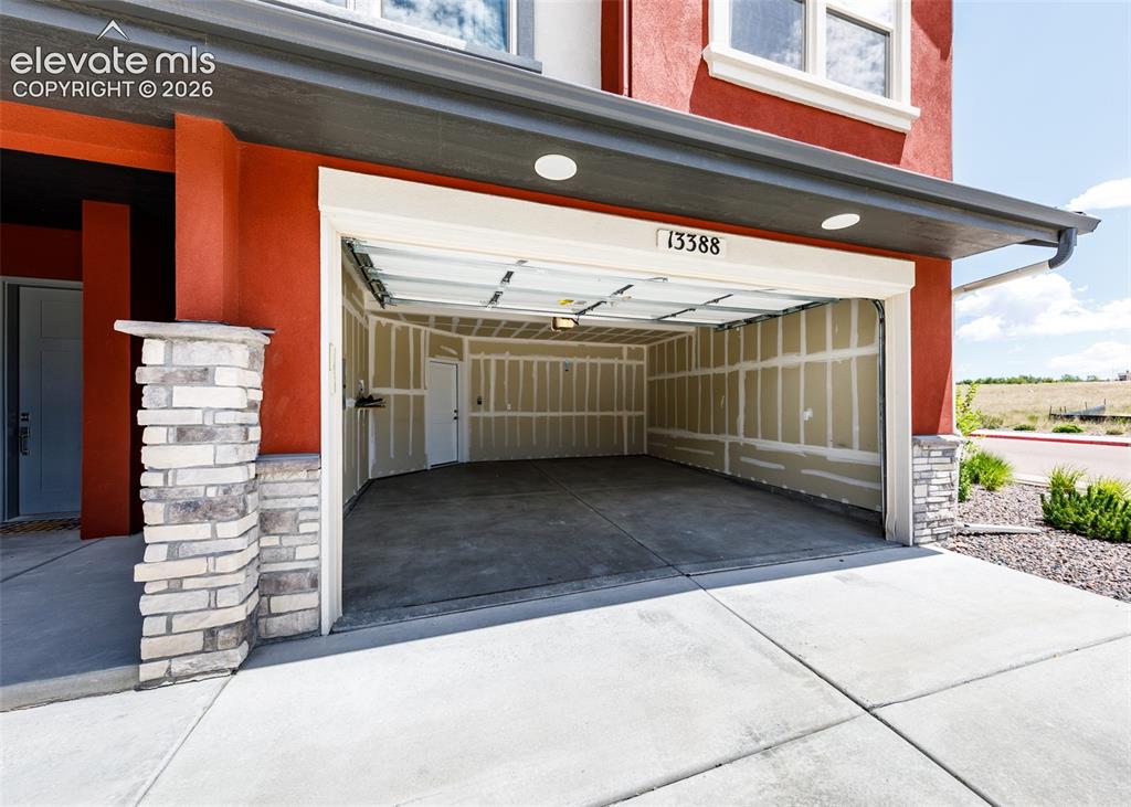Image 46 of 50: Spacious garage with concrete flooring, exposed wall studs, and overhead li