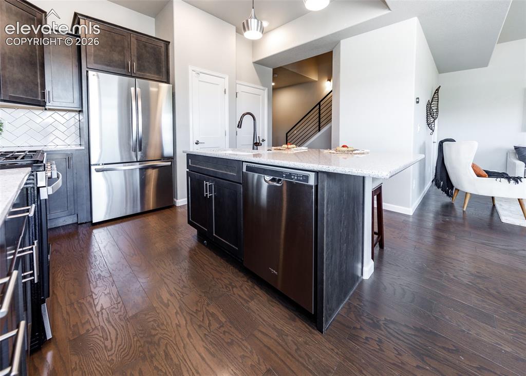 Image 6 of 50: Modern kitchen featuring dark wood-finish cabinetry, stainless steel applia