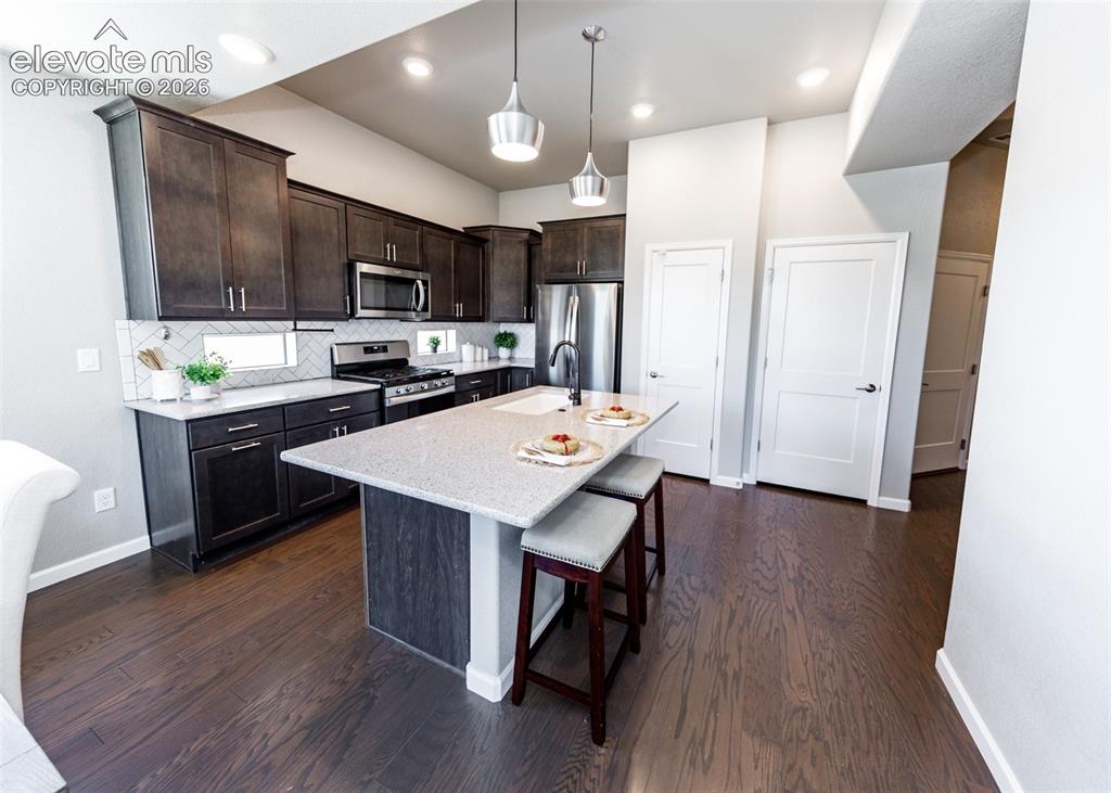 Image 8 of 50: Modern kitchen featuring dark wood-finish cabinetry, stainless steel applia