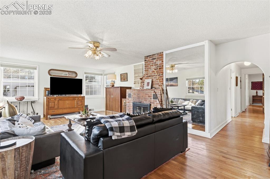 Image 12 of 50: The spacious Living Room showcases gorgeous hardwood flooring and a firepla