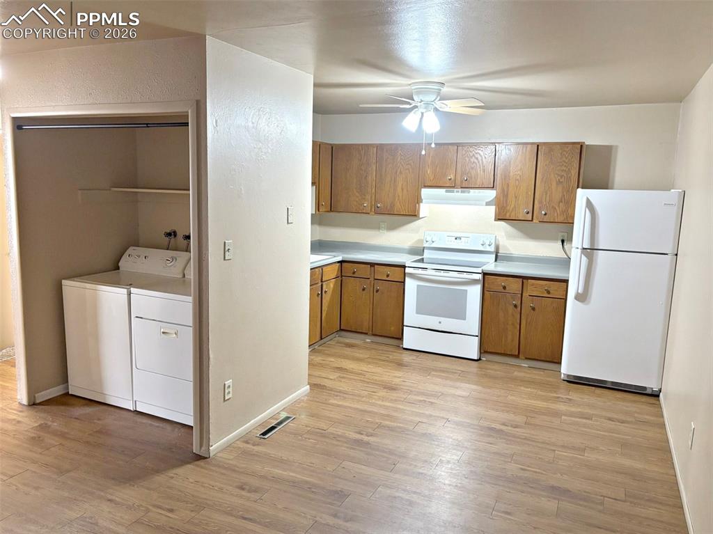 Image 10 of 17: Kitchen featuring white appliances, wood finish cabinetry, light countertop