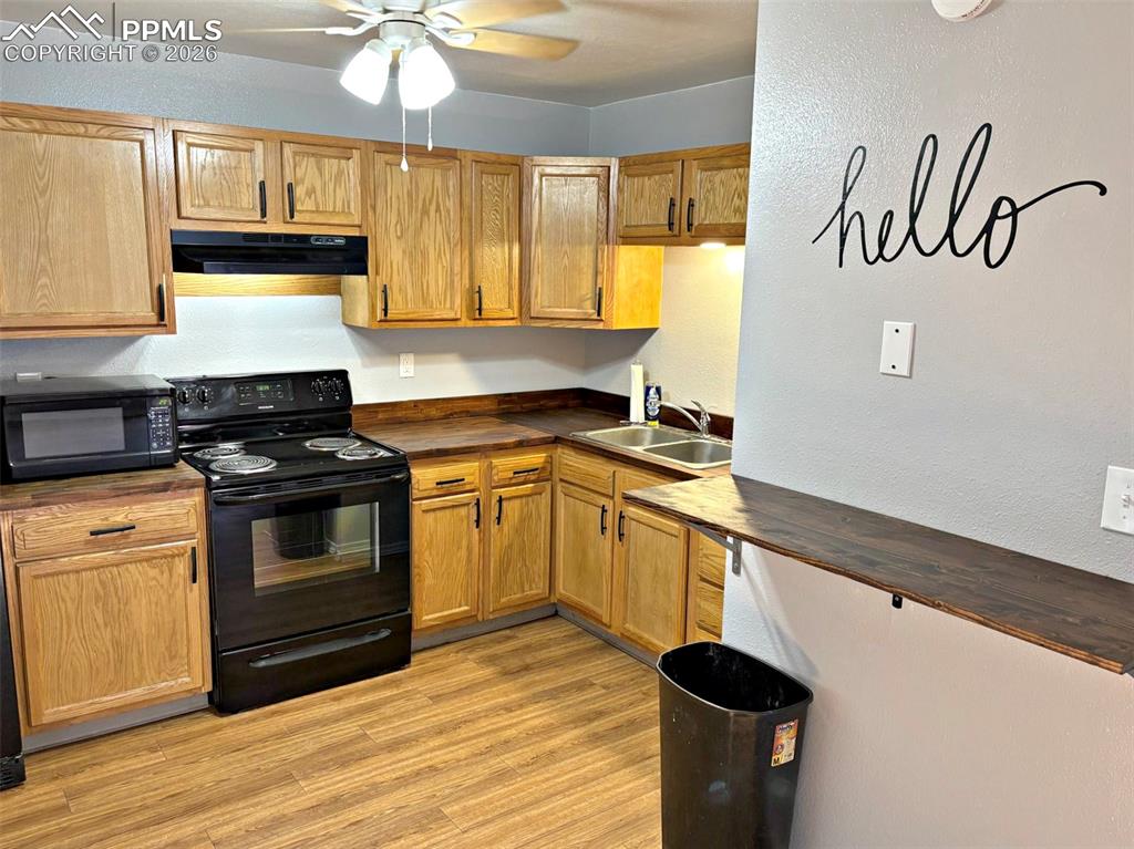 Image 14 of 17: Kitchen with black appliances, butcher block countertops, a ceiling fan, li