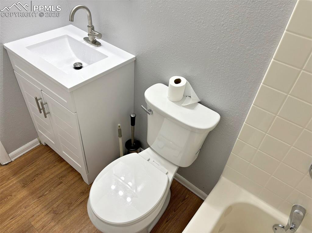 Image 17 of 17: Bathroom featuring vanity, a textured wall, a bath, and wood finished floor