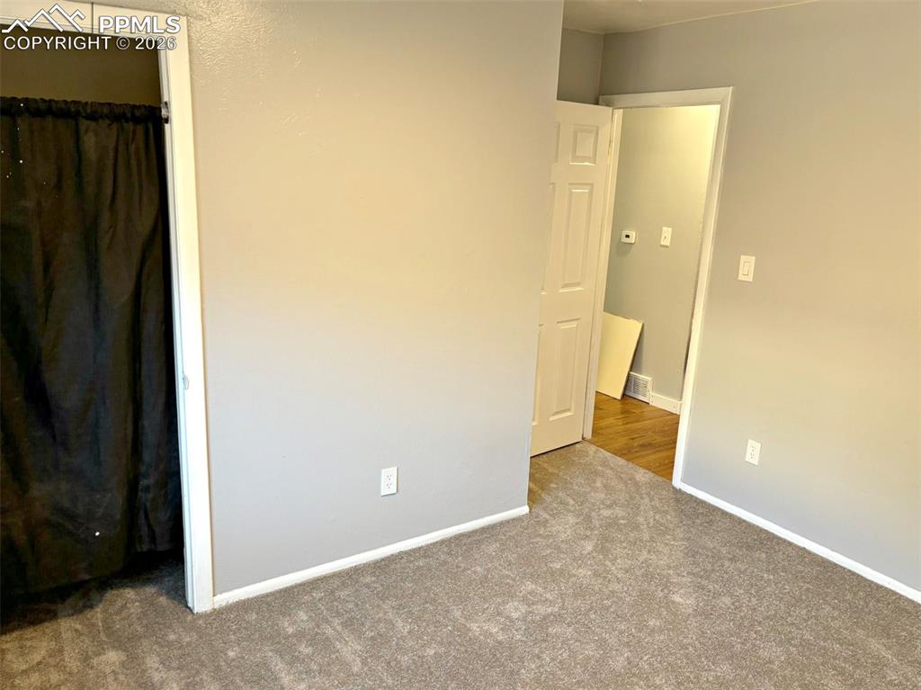Image 2 of 17: Unfurnished bedroom featuring dark carpet and baseboards