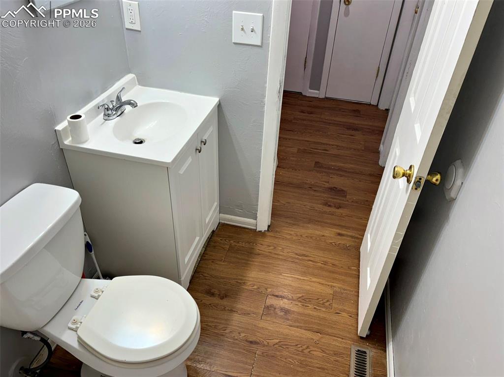 Image 5 of 17: Half bath featuring dark wood-type flooring, vanity, and a textured wall