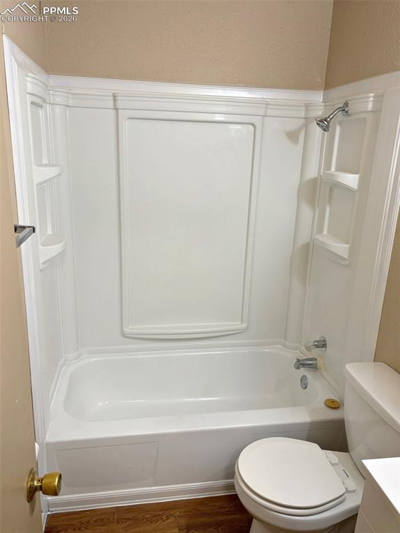 Image 8 of 17: Bathroom featuring washtub / shower combination, dark wood-style floors, an
