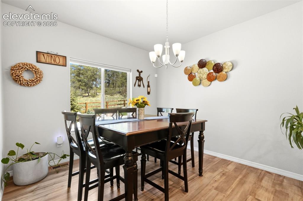 Image 10 of 44: Dining area featuring wood-finish flooring, a contemporary chandelier, and 
