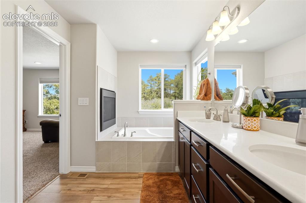 Image 12 of 44: Bathroom featuring a dual vanity with white countertop, integrated soaking 