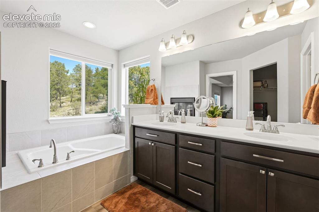 Image 13 of 44: Bathroom featuring a built-in soaking tub with surrounding tile, dual windo