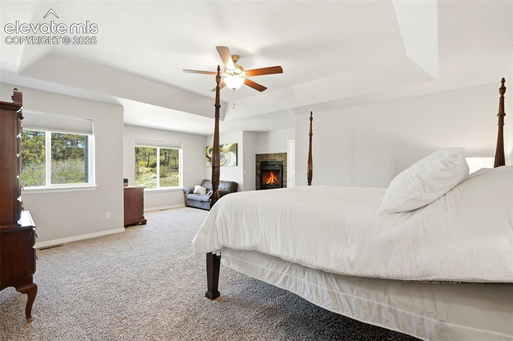 Image 16 of 44: Spacious bedroom featuring a tray ceiling, ceiling fan with integrated ligh
