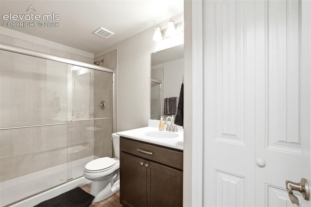 Image 30 of 44: Bathroom featuring a glass-enclosed shower with tile surround, a dark wood-