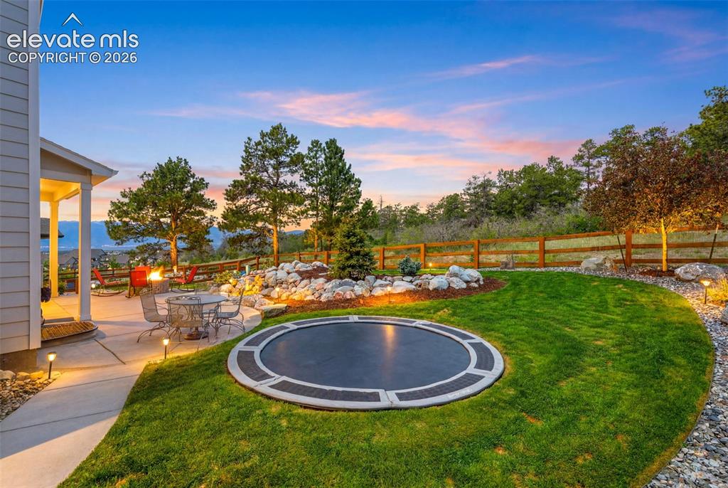 Image 33 of 44: Expansive backyard featuring a built-in trampoline, concrete patio, and a r