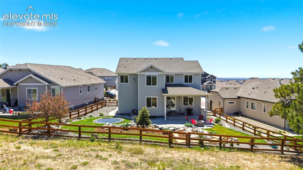 Image 38 of 44: Rear exterior featuring a two-story design with light gray siding, a covere