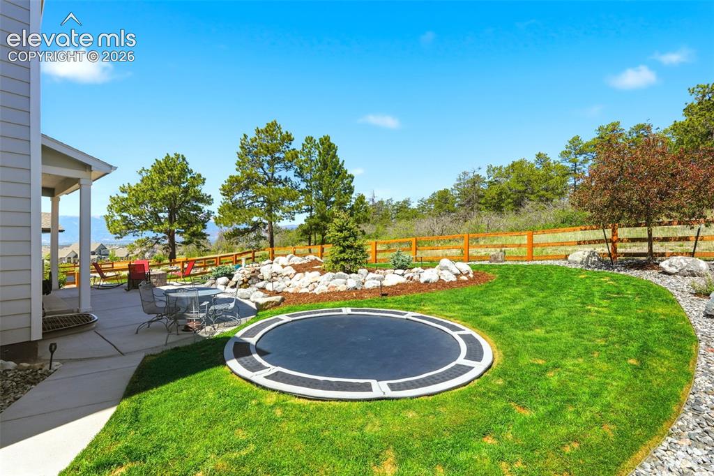 Image 39 of 44: Expansive green lawn featuring an in-ground trampoline