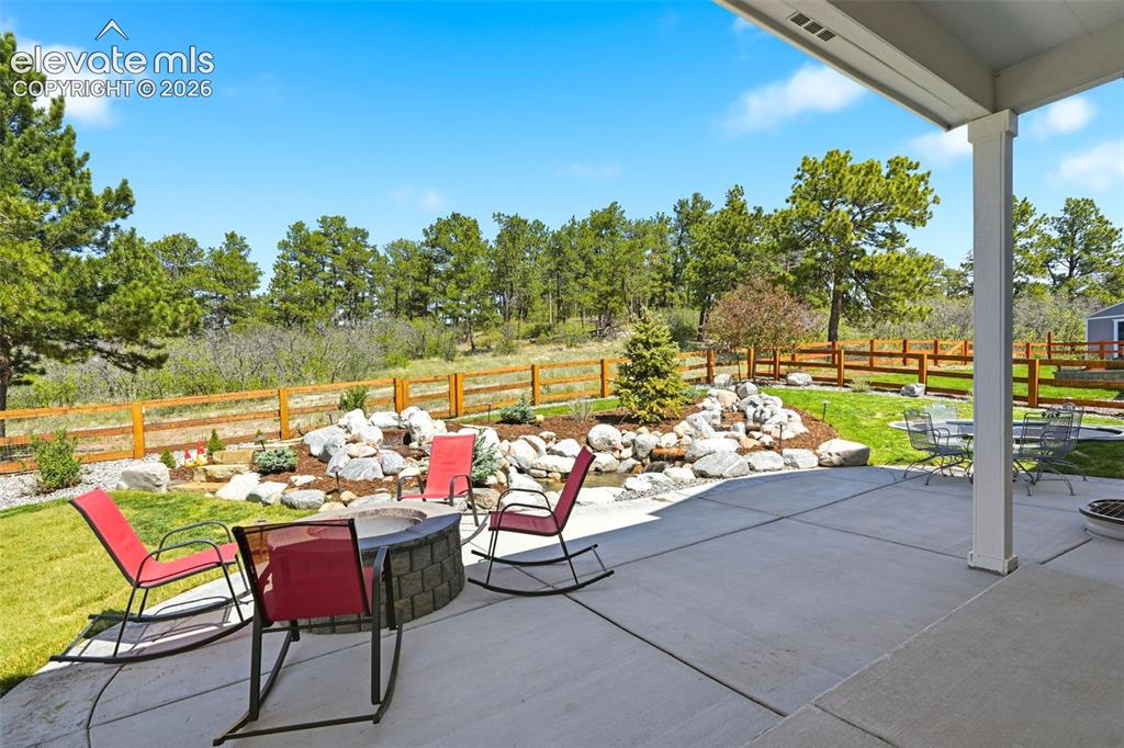 Image 41 of 44: Expansive concrete patio with a built-in fire pit