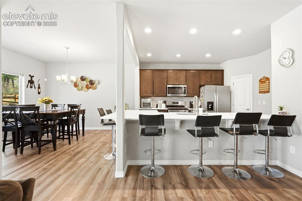 Image 6 of 44: Open-concept kitchen featuring wood-finish flooring, recessed lighting, whi