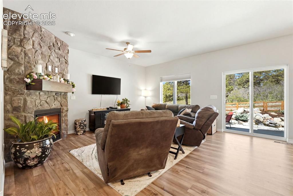 Image 7 of 44: Open concept living area featuring wood-finish flooring, a stone-faced fire