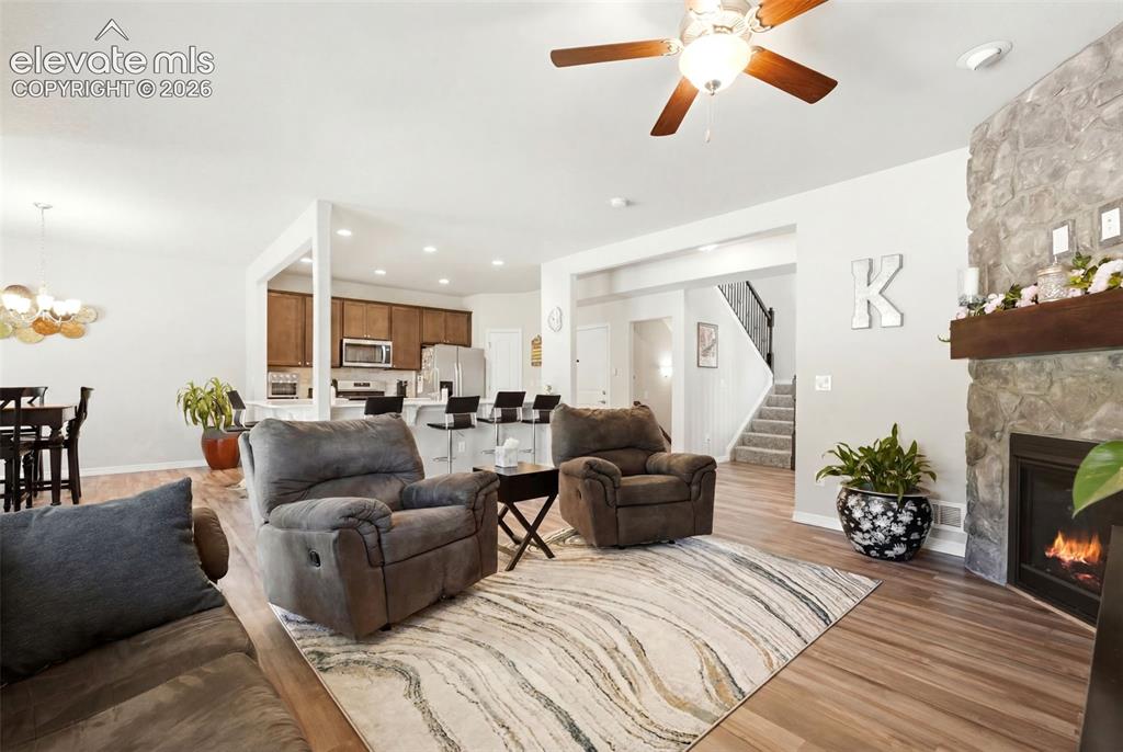 Image 8 of 44: Open concept living area featuring wood-finish flooring, a stone-faced fire