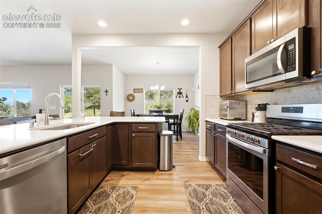 Image 9 of 44: Kitchen featuring dark wood cabinetry, stainless steel appliances, a white 