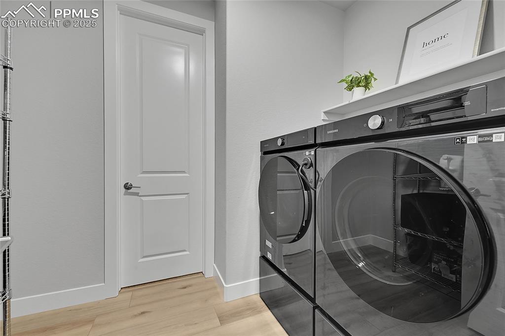 Image 16 of 44: Washroom with washing machine and clothes dryer and light wood-style floors