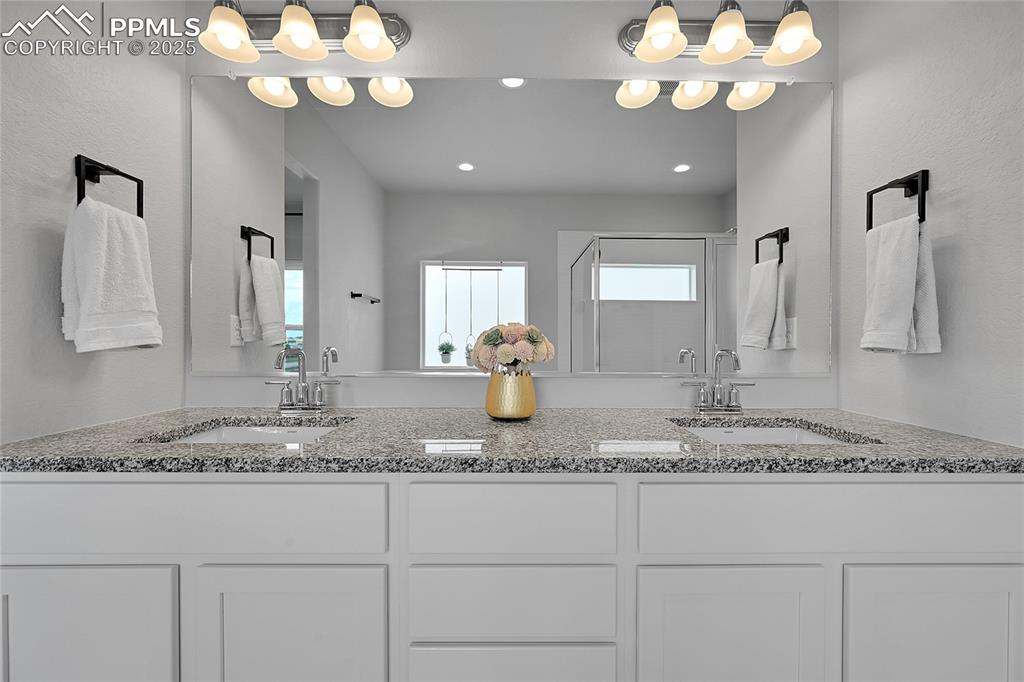Image 20 of 44: Full bathroom featuring double vanity, a shower stall, and recessed lightin