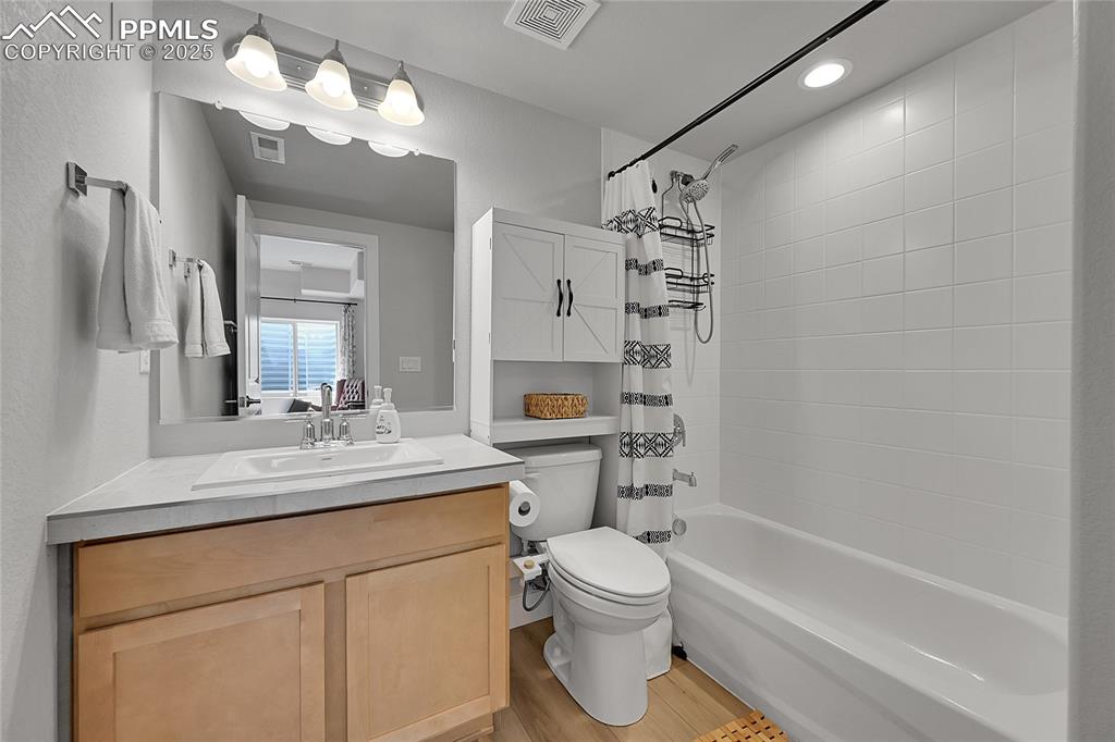 Image 30 of 44: Bathroom with wood finished floors, vanity, shower / bathtub combination wi