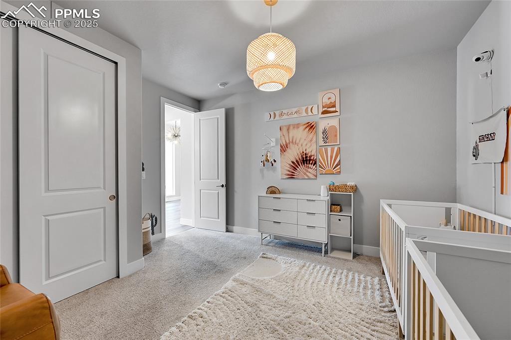 Image 32 of 44: Carpeted bedroom featuring baseboards and a crib