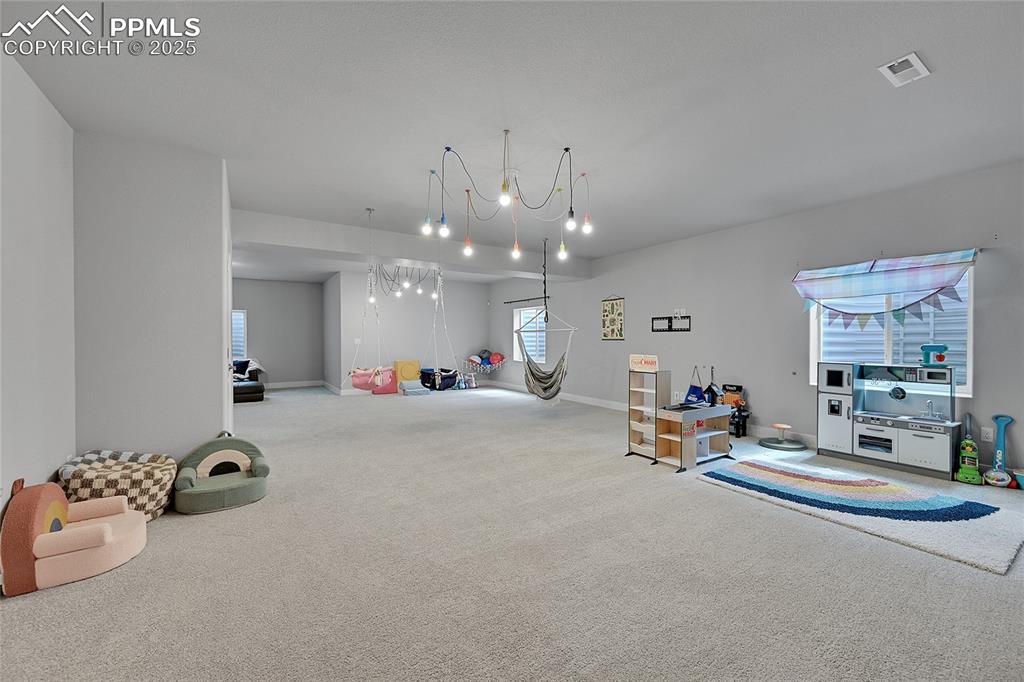 Image 33 of 44: Recreation room with carpet floors and a chandelier